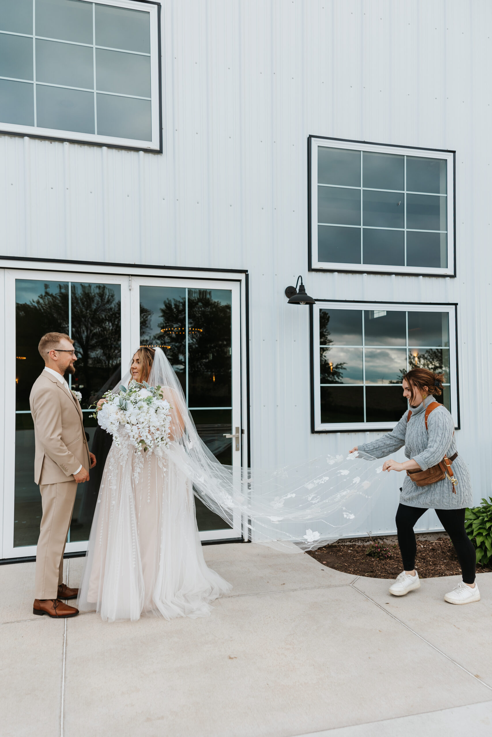 photographer adjusting brides veil for photos