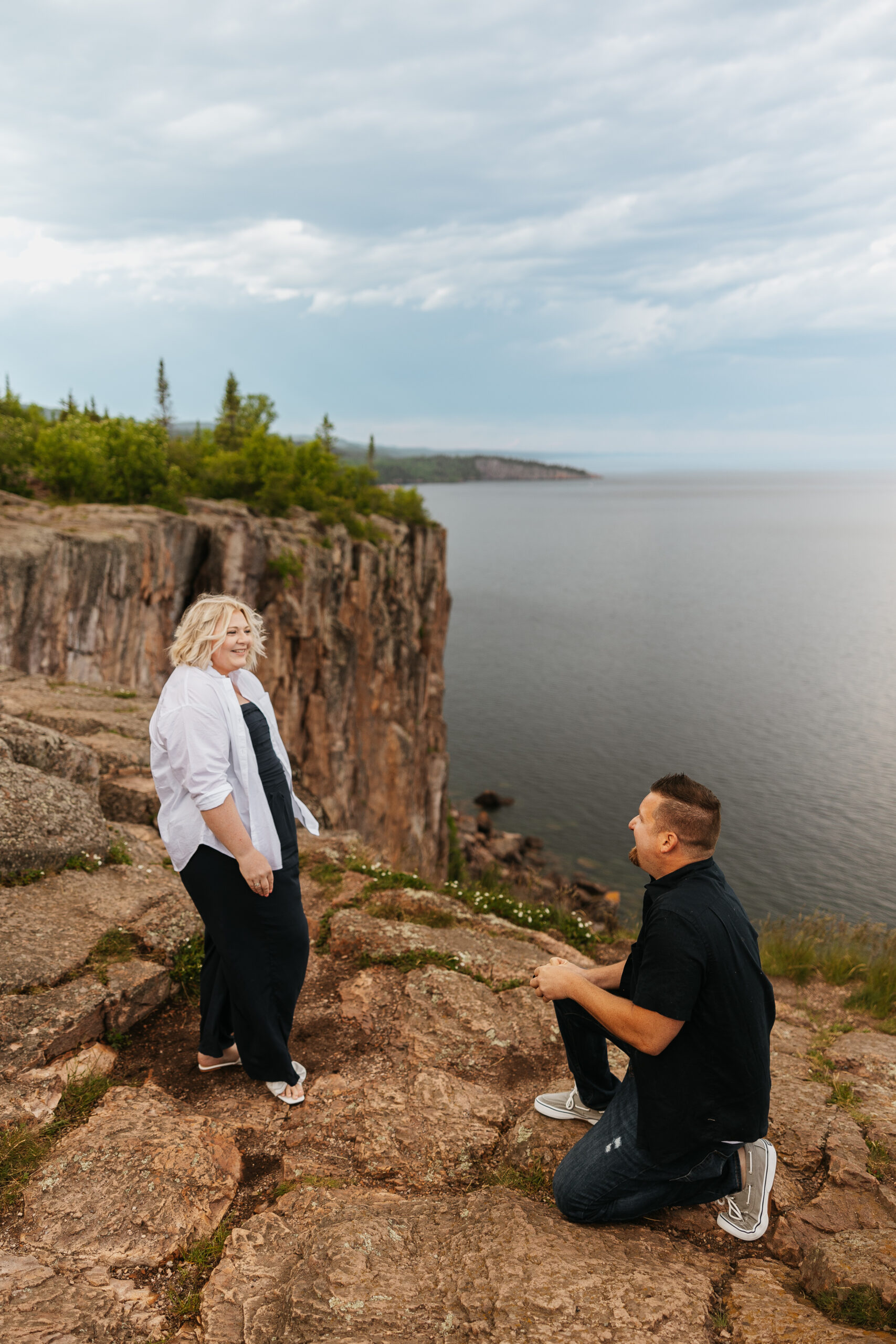 couple standing at palisade head on cliff while he proposes