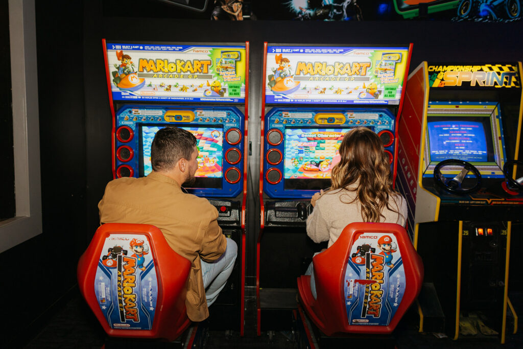 couple playing Mario kart arcade game together inside arcade during a photo session
