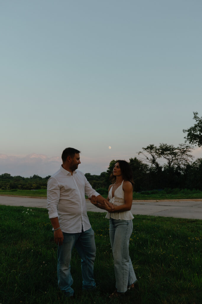 Couple during blue hour with the moon behind them